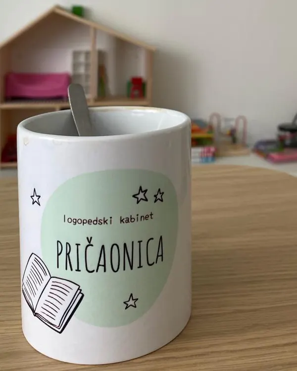 Šalica sa zelenim logom Pričaonice na stolu u kabinetu